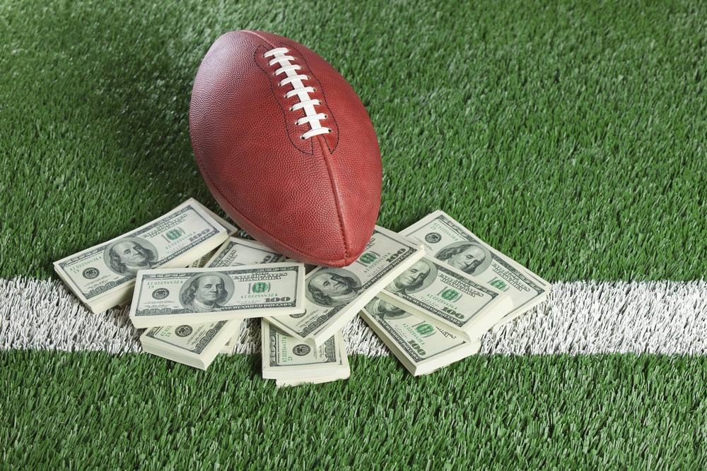 Photograph of football with stacks of 100 dollar bills